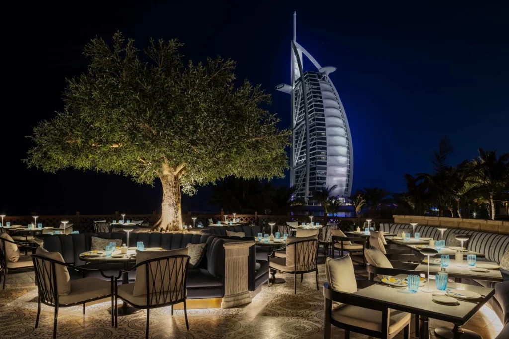 Fake olive tree in Dubai adds ambience to a rooftop restaurant terrace overlooking Burj Al Arab; ideal artificial olive trees for hotels.